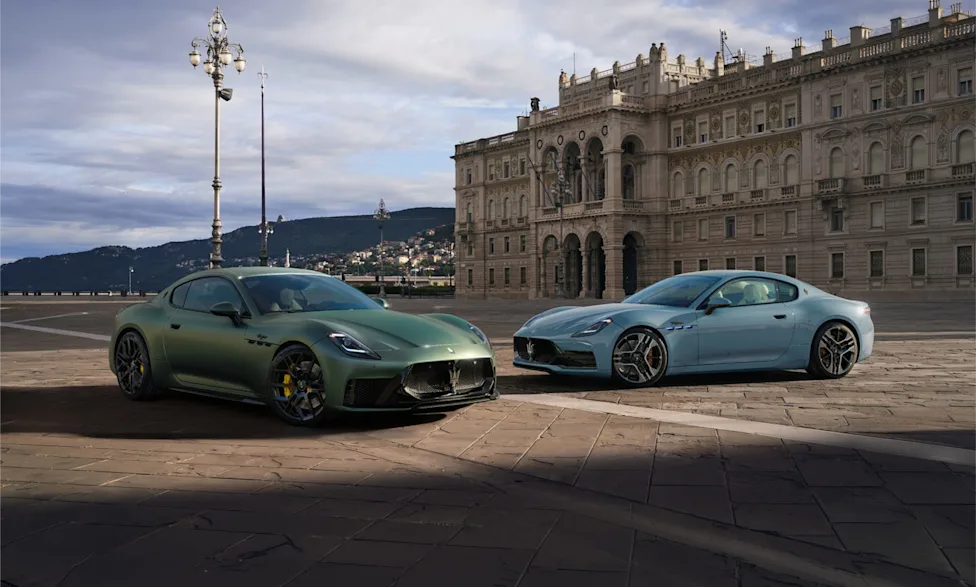Two Maserati GranTurismo models parked in a plaza in front of a historic building.